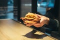 An appetizing chicken burger in female hands in a fast food restaurant.