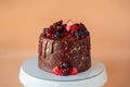 Appetizing chocolate cake decorated with strawberries, blueberries and a pomegranate on an orange background Royalty Free Stock Photo