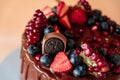 Appetizing chocolate cake decorated with strawberries, blueberries and a pomegranate on an orange background Royalty Free Stock Photo