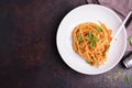 Appetizing classic Italian spaghetti pasta with tomato and basil sauce and fork arranged on a white plate. On a dark wooden table Royalty Free Stock Photo