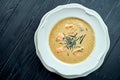 Appetizing coconut soup with salmon, nori and sesame seeds, served in a white plate on a dark wood background. Pan-Asian cuisine