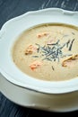 Appetizing coconut soup with salmon, nori and sesame seeds, served in a white plate on a dark wood background. Pan-Asian cuisine