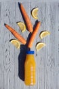 Appetizing composition of a bottle of orange juice, slices of lemon and carrots