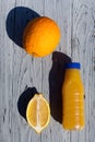 Appetizing composition of a bottle of orange juice, a whole orange, half of a lemon