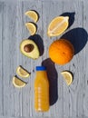 Appetizing composition of a bottle of orange juice, a whole orange, slices and half of a lemon, avocado halves with a stone