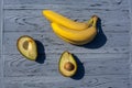 An appetizing composition of ripe yellow bananas and two halves of an avocado with a stone