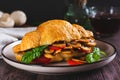 Appetizing croissant stuffed with fried champignons and tomatoes on a plate