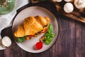 Appetizing croissant stuffed with fried champignons and tomatoes on a plate top view