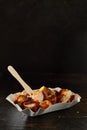 Appetizing currywurst in disposable container on black background