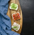 appetizing delicious vegetarian sandwiches with fresh cucumber, radish, tomato and microgreens on black slate background