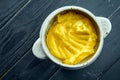 Appetizing and dietary side dish - mashed potatoes served in a white pot on a black wooden background