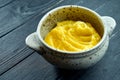 Appetizing and dietary side dish - mashed potatoes served in a white pot on a black wooden background