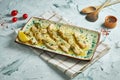 An appetizing dish of Italian cuisine - turkey Piccata with parmesan and olives in a white plate on a gray background. Close up