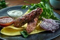 An appetizing dish of Turkish cuisine - chicken kebab from minced meat with pita bread, cilantro, onions and sauces, served in a Royalty Free Stock Photo