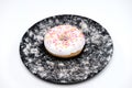 Appetizing donut with sprinkles lie on a black ceramic plate. Royalty Free Stock Photo