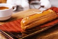Appetizing eclair with caramel glaze and peanuts and coffee Royalty Free Stock Photo