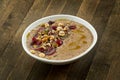 Appetizing flaxseed porridge with olive oil, seeds, grapes and hazelnuts in a white bowl on a wooden background. Vegetarian food.