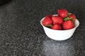 Appetizing fresh strawberry in a white bowl on a gray background.