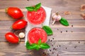 Appetizing fresh tomato juice with basil leaves in glasses and ingredients for its preparation on a wooden table Royalty Free Stock Photo