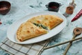 Appetizing freshly baked calzone pizza with crisp in a white plate on a gray background. Restaurant serving