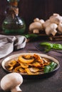 Appetizing fried champignons and basil leaves on a plate on the table vertical view Royalty Free Stock Photo