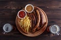 Appetizing grilled sausages and french fries served with spicy t Royalty Free Stock Photo