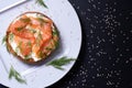 Appetizing half of a bun with smoked fish, fresh cream, sprinkled with dill and sesame seeds