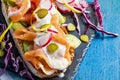 Appetizing and healthy smoked salmon with avocado, vegetables radish, lemon, red cabbage, pickle and yogurt sauce on toasted