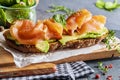 Appetizing and healthy smoked salmon with avocado and vegetables spinach sprouts, tomatoes, thyme on toast. Homemade look Royalty Free Stock Photo