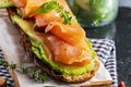 Appetizing and healthy smoked salmon with avocado and vegetables spinach sprouts, tomatoes, thyme on toast. Homemade look Royalty Free Stock Photo