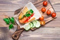 Appetizing hot dog made from fried sausage, rolls and fresh vegetables, wrapped in parchment paper on a cutting board Royalty Free Stock Photo