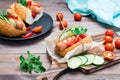 Appetizing hot dog made from fried sausage, rolls and fresh vegetables, wrapped in parchment paper on a cutting board Royalty Free Stock Photo