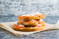 Appetizing hot sandwiches with a crispy crust, with hot sauce, tomato, cheese and sausage, on baking paper Royalty Free Stock Photo