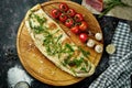 Appetizing italian pizza calzone with different fillings in a composition with ingredients on a wooden board on a black background Royalty Free Stock Photo