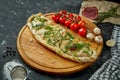 Appetizing italian pizza calzone with different fillings in a composition with ingredients on a wooden board on a black background Royalty Free Stock Photo