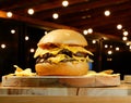 Appetizing juicy burger with crispy chips on a wooden cutting board with a bokeh background