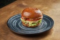 Appetizing and juicy cheeseburger with, chicken burger, tomato, caramelized onions and melted cheese in a black ceramic plate on a