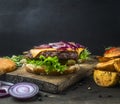 Appetizing juicy home burger with beef, salad, pickled cucumbers, cheese and onion,potato ,wedges, bun with sesame, on vintage c