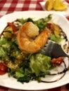 Appetizing juicy shrimp on a fork on the background of fresh salad
