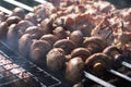 Appetizing mushrooms close-up on the grill on the background of roasting kebab Royalty Free Stock Photo