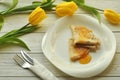 Appetizing pancakes with fruit jam, a cup of tea with lemon, yellow tulips, fork and knife Royalty Free Stock Photo