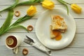 Appetizing pancakes with fruit jam, a cup of tea with lemon, yellow tulips, fork and knife Royalty Free Stock Photo