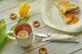 Appetizing pancakes with fruit jam, a cup of tea with lemon, yellow tulips, fork and knife Royalty Free Stock Photo