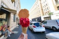 Appetizing pink berry ice cream in waffle cone in female hand over Rome city view. Tasty ice cream like a symbol of summer and