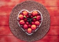 Appetizing plate of seasonal ripe fresh fruit in a white heart-shaped plate - healthy eating with apricots, grapes, strawberries,