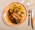 Pork knuckle baked in oven with boiled potatoes in white plate