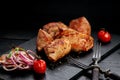 Appetizing pork shish kebab on a black stone cutting board. Red onion, cherry tomatoes and two forks. Soft focus