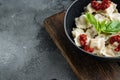 Appetizing ravioli with tomato sauce cheese and basil with basil parmesan and tomatoe in black bowl on gray background with