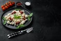 Appetizing ravioli with tomato sauce cheese and basil with basil parmesan and tomatoe on black plate on black background with