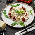 Appetizing ravioli with tomato sauce cheese and basil with basil parmesan and tomatoe on white plate on old dark wooden table